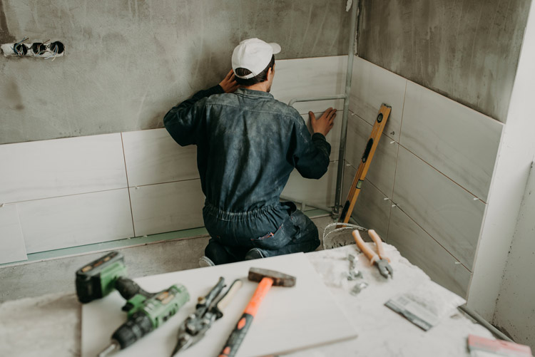 Person putting up tile in bathroom