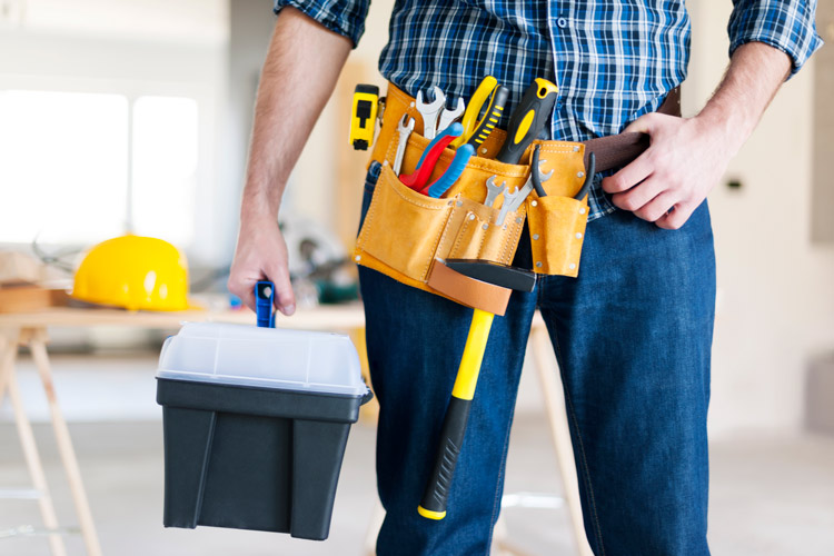 Man standing with toolbelt full of tools.