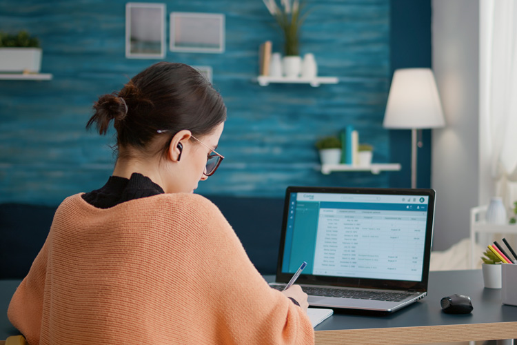 Women sitting at computer with earbuds in working remotely from home.